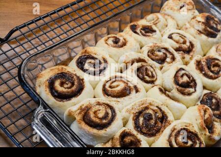 A view of fresh baked cinnamon rolls cooling on a wire rack waiting to be frosted Stock Photo
