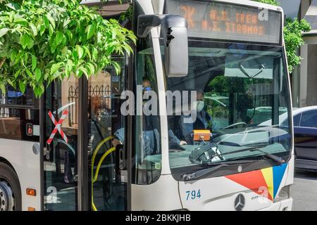 Bus driver wearing COVID-19 protective mask. OASTH public transportation vehicle at stop of Thessaloniki Urban Transport Organization in Greece. Stock Photo