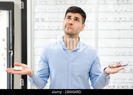 Pensive man choosing between eyeglasses and contacts Stock Photo