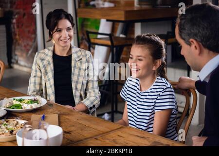 A family of three enjoying their time in a cafe. Stock Photo