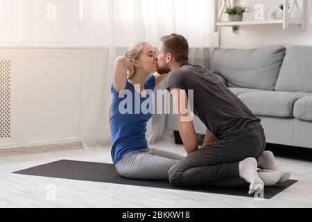 Happy woman doing abs exercise and kissing her boyfriend Stock Photo