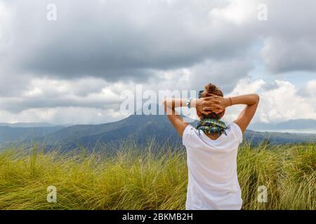 A woman watching the view of volcano Batur (Gunung Batur) and Lake Batur (Danau Batur). Kintamani, Bangli, Bali, Indonesia. Stock Photo