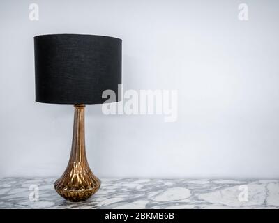 Vintage table lamp on marble table. Luxury lamp designed with black fabric and gold on white background with copy space. Stock Photo