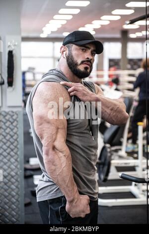 strong bearded man in hoodie lifting heavy barbell deadlift among