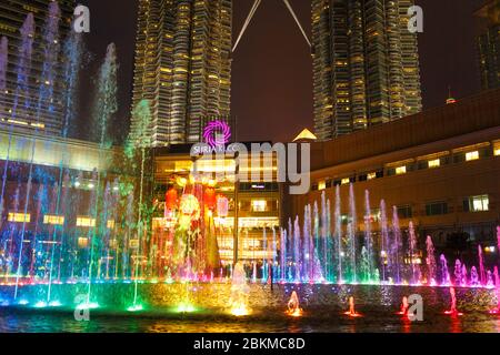 Multi-colored dancing fountains near the twin towers of Petronas in Kuala Lumpur. Stock Photo