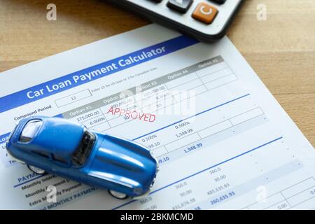 Car loan agreement approved by financial bank.Payment contract  calculator form.A  blue  car with paper  on the table with copy space. Stock Photo