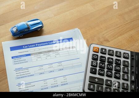 Car loan agreement approved by financial bank.Payment contract  calculator form.A  blue  car with paper  on the table with copy space.