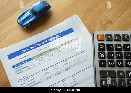 Car loan agreement approved by financial bank.Payment contract  calculator form.A  blue  car with paper  on the table with copy space.