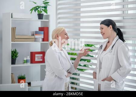 Two doctors in white robes talking in the office Stock Photo