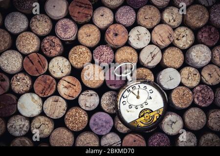 Antique pocket watch on old Used corks plugs from various types of wine on dark background Stock Photo