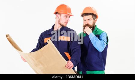 Architect and build concept. Men in helmets with blueprint on white background. Architects in hard hat on thoughtful faces looks at drawing, plan, project. Builder, engineer, architect work at site. Stock Photo