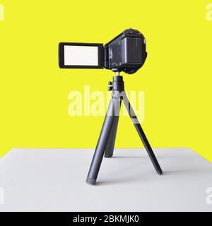Digital video camera on a tripod isolated on a yellow. Blank for designers Stock Photo
