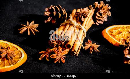 Background of dry slices of orange, cinnamon and star anise, ingredients for preparation mulled wine on black background Stock Photo