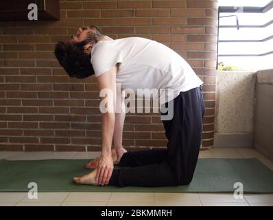 Young handsome caucasian man practicing yoga, stretching. Exercise at home concept. Stock Photo