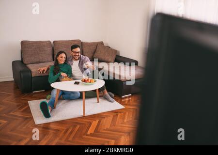Couple is relaxing at home. They are watching tv. Stock Photo