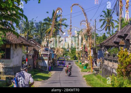 BALI, INDONESIA - 16TH APRIL 2017:  Streets in Bali. Penjor Poles can be seen as part of the annual Galungan Celebration. People can be seen. Stock Photo