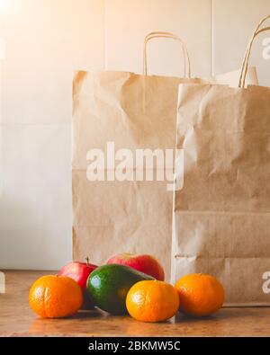 Paper bags, fresh vegetables and fruits next to a mobile phone on the table with kitchen utensils. Concept of shopping, healthy eating and vegetariani Stock Photo