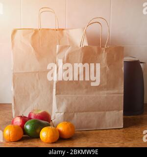 Paper bags, fresh vegetables and fruits next to a mobile phone on the table with kitchen utensils. Concept of shopping, healthy eating and vegetariani Stock Photo