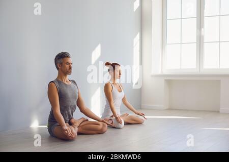 Yoga couple people hand sitting relaxation in lotus field on floor in studio class. Stock Photo