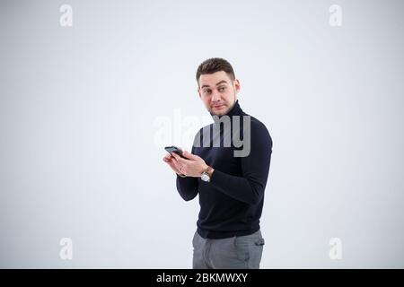 Serious guy businessman in black clothes finds out important questions by phone. Working day concept
