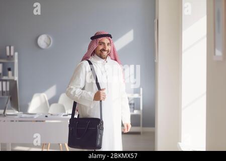 Arab man with black bag smiling in office. Stock Photo