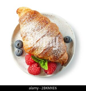 freshly baked sweet croissant on white plate isolated on white background, top view Stock Photo