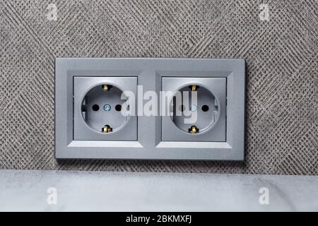 Socket gray with ground with an input for two devices. She is on the gray wall above the counting table. Electricity and repair concept Stock Photo