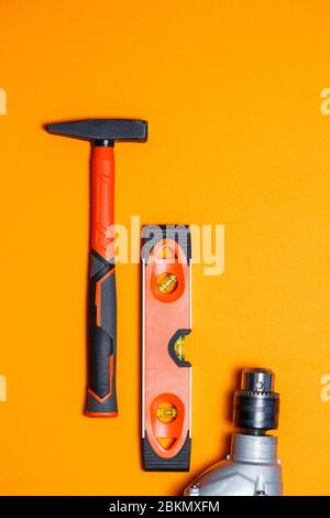 Tools for repairing home use. Hammer for nails, level and drill on an orange background. Toolkit for the wizard Stock Photo