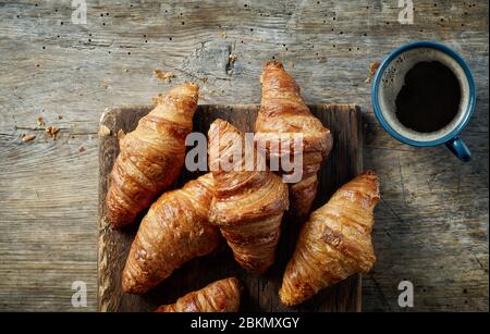 freshly baked croissants and cup of coffee on wooden table, top view Stock Photo