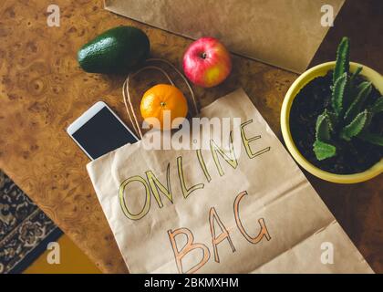 Paper bag with inscription - Online bag, different fresh fruits, vegetables on a kitchen table. Online shopping and contactless delivery concept. Top Stock Photo