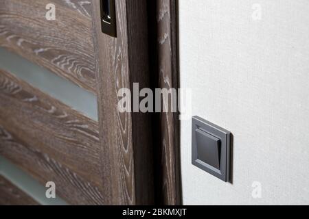 Two-key switch of gray color near the door, plastic mechanical switch. The light switch is installed after repair. Energy saving concept. Close up lig Stock Photo