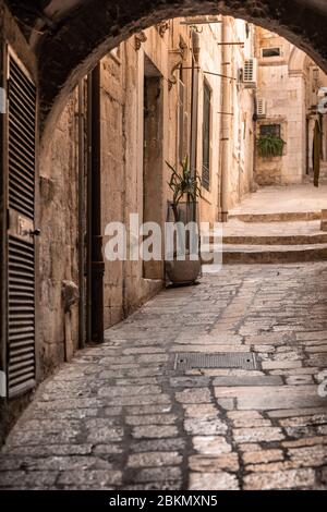 A small alley with old limestone pavements in the old town in Dubrovnik, Dalamtia, Croatia on a sunny day in summer. Ancient street with stairs in the Stock Photo