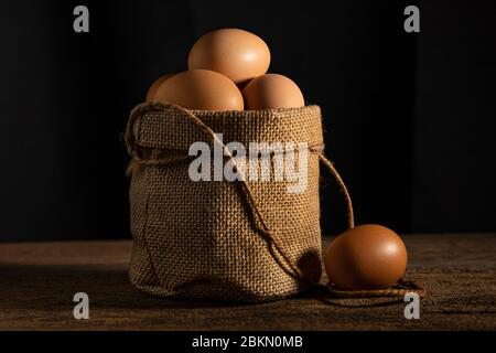 Close up egg in cotton sack on wooden table background Stock Photo