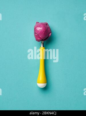 Ice cream spoon with berry ice cream on turquoise background Stock Photo