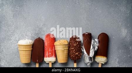 Chocolate ice cream popsicles and fruit ice cream with cones on gray cold stone background. Copy space for text. Stock Photo