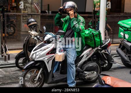 Grab food delivery motorcycle rider with face mask during Covid 19 pandemic, Bangkok, Thailand Stock Photo