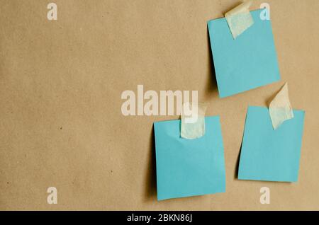 Colored paper for notes attached to the wall. Three turquoise blank forms with adhesive tape on a plain wall. Angled side view. Training, business, me Stock Photo