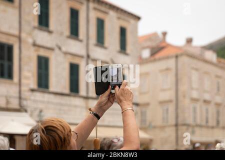Dubrovnik, Croatia, September 19th 2019. An elderly senior aged woman photographing the Old Town with her phone. Tourist destination, Dalmatia, Europe Stock Photo