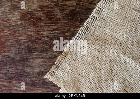 Old burlap fabric napkin on brown wooden background. Multitask background with place for text. Top view. Stock Photo