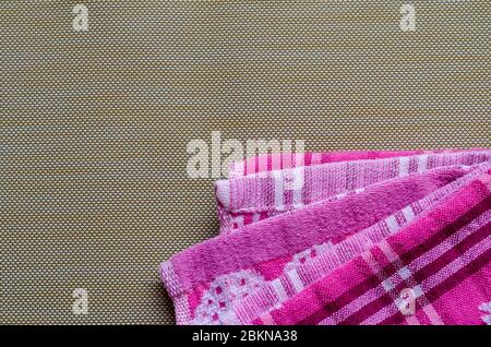 Pink towels on a brown background. Colorful kitchen towels. Abstract multitask background. View from above. Place for text. Stock Photo