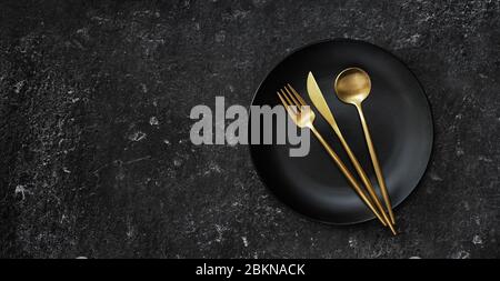 A black plate with golden cuttlery captured from aboce Stock Photo