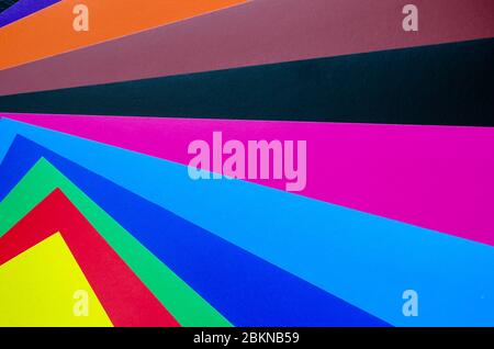 Multicolored paper background. Paper sheets of rainbow colors close-up. Geometric multitask background. Place for text. View from above. Stock Photo