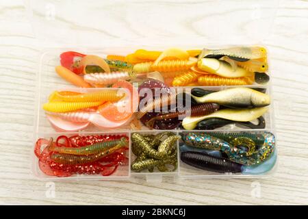 Colorful silicone fishing baits with plummets on wooden table