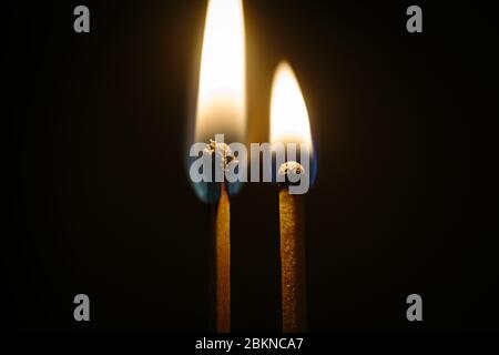 Couple of matches burning together with heat flame isolated on a black background Stock Photo