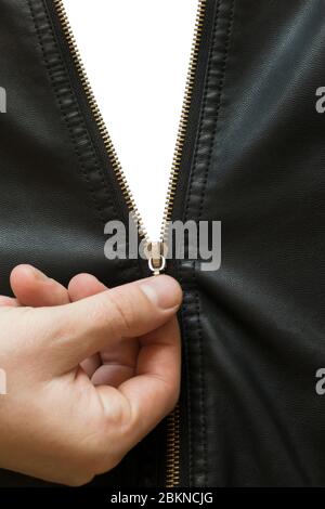 a man's hand unzips a metal zipper on a black leather jacket, on an isolated background Stock Photo