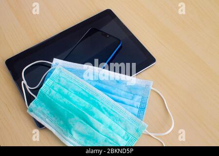 Blue and green mask lying on smartphone and digital tablet on table Stock Photo