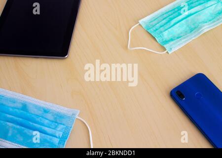 Blue and green mask smartphone and digital tablet lying in corners on wooden table Stock Photo