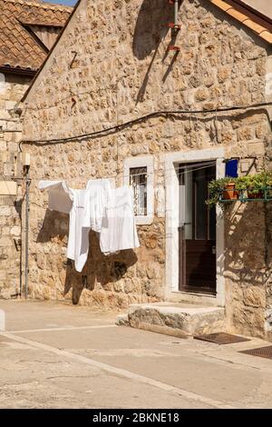 Fresh white laundry with towels hanging outside in front of a rustic old typical mediterranean house in the Old Town of Dubrovnik in Dalmatia, Croatia Stock Photo