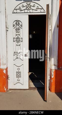 Opened white door and wall decorated by curly pattern gratings and lattice. Classic architecture of European city Odessa of Ukraine. Stock Photo