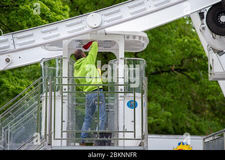 05 May 2020, Saxony-Anhalt, Magdeburg: An employee of the Boos brothers cleans a gondola of the Ferris wheel, which was built in the Rotehornpark next to the Albin-Müller-Tower. The operators are currently working out a concept to comply with the distance rules. At the base, a snack bar has already opened and sold food. However, eating is not permitted within a radius of 50 metres. The Ferris wheel had been set up in the past weeks and is operated by the Boos brothers from Magdeburg. Actually the ride should have been operated at other fairs at the moment. But they had been cancelled due to th Stock Photo